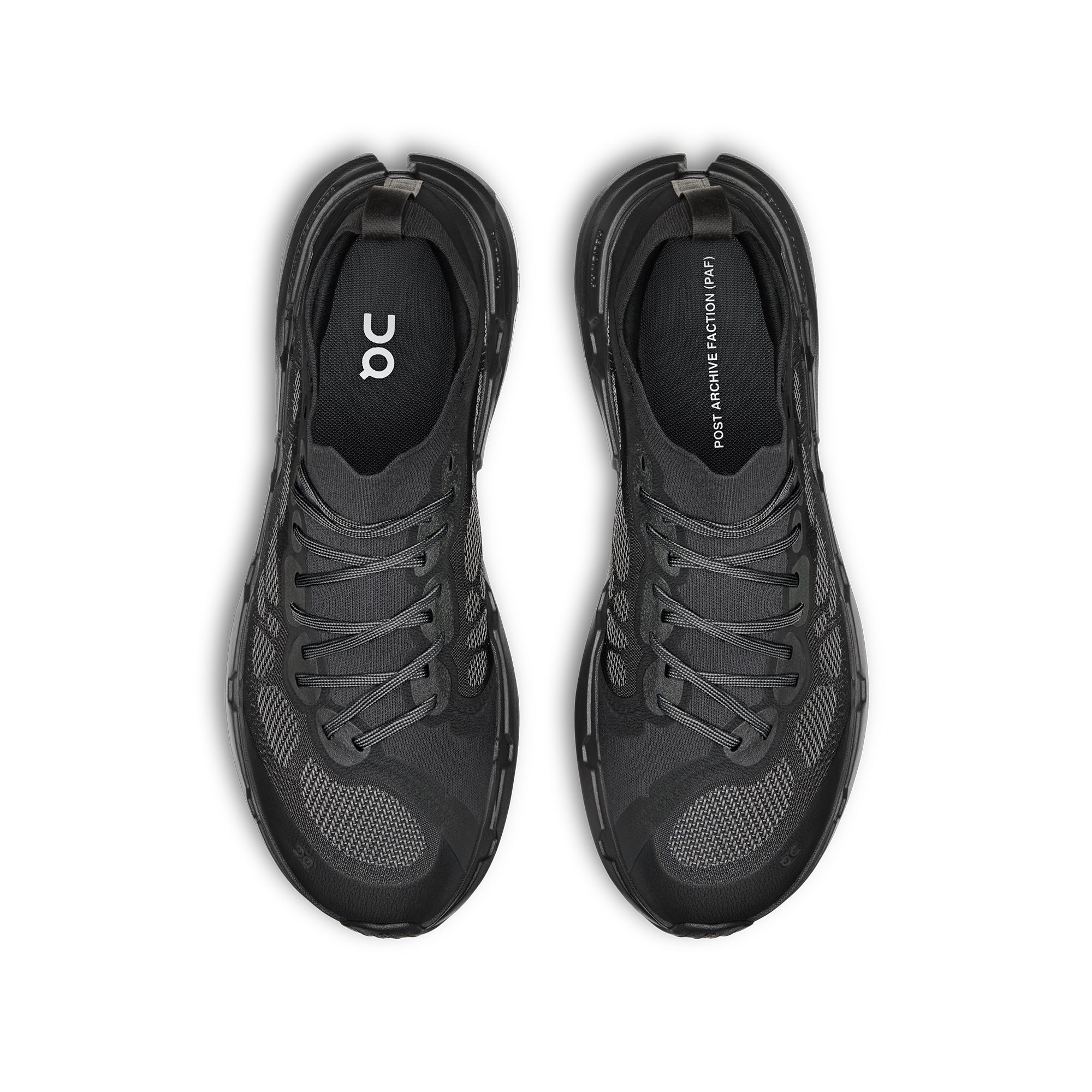 A pair of black and dark gray athletic sneakers shown from a top-down view on a white background. The brand 'on' is visible on the insole of both shoes.